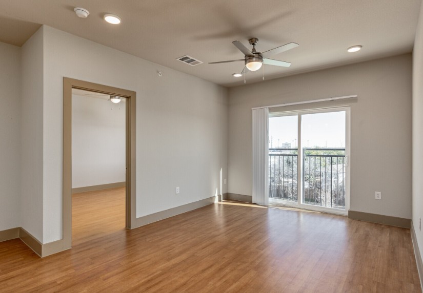 A room with a ceiling fan and sliding glass doors.